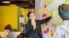 A woman looking at the post-it notes on a board.